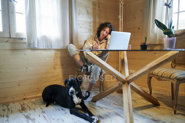 Mitte erwachsene Frau mit Hund benutzt Laptop zu Hause — Stockfoto