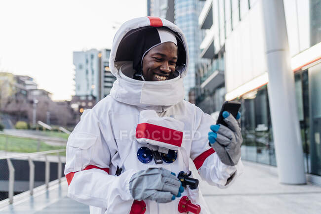 Усміхаючись самець астронавт за допомогою мобільного телефону. — стокове фото