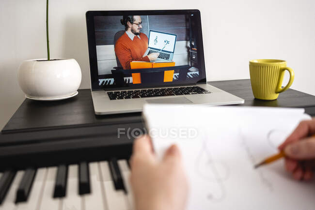 Mid adult woman writing musical notes during online tutorial on laptop at home — Stock Photo