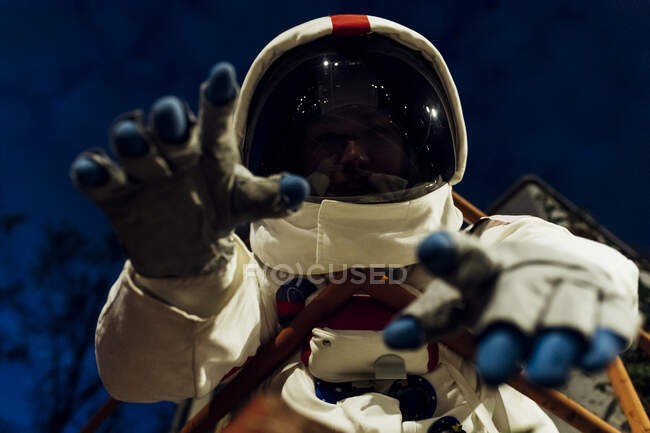 Young female astronaut in space suit gesturing at night — Stock Photo