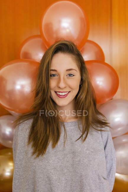 Mujer de pie por globos decoración en la pared en casa - foto de stock