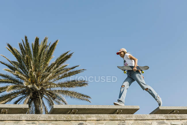 Mitte erwachsene Frau läuft mit Skateboard auf Stützmauer — Stockfoto