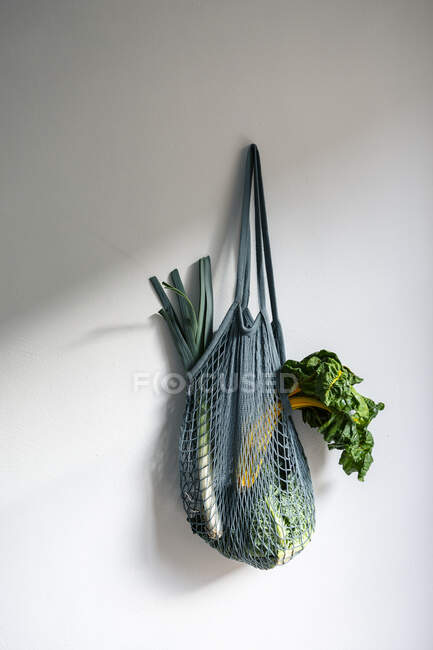 Legumes em saco de malha pendurado na parede — Fotografia de Stock