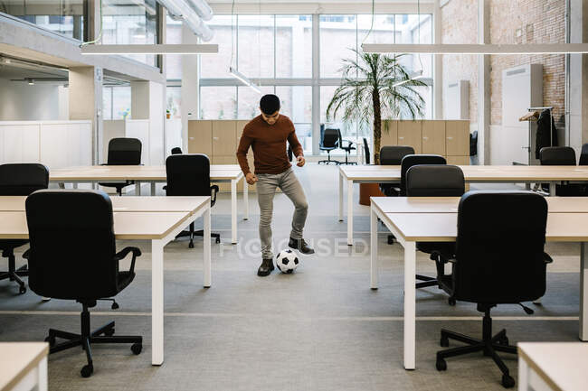 Молодой предприниматель играет с футбольным мячом в офисе — стоковое фото