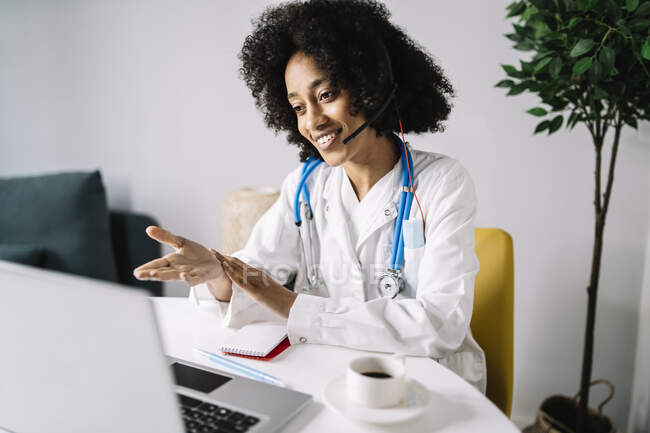 Profesional médico femenino haciendo consulta en línea en el ordenador portátil en casa - foto de stock