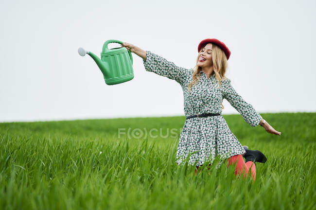 Весела жінка поливає траву на лузі — стокове фото