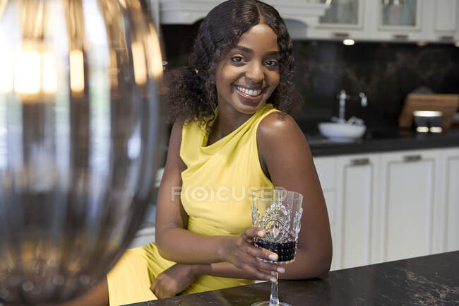 Porträt einer glücklichen jungen Frau mit einem Glas Rotwein in der Küche — Stockfoto