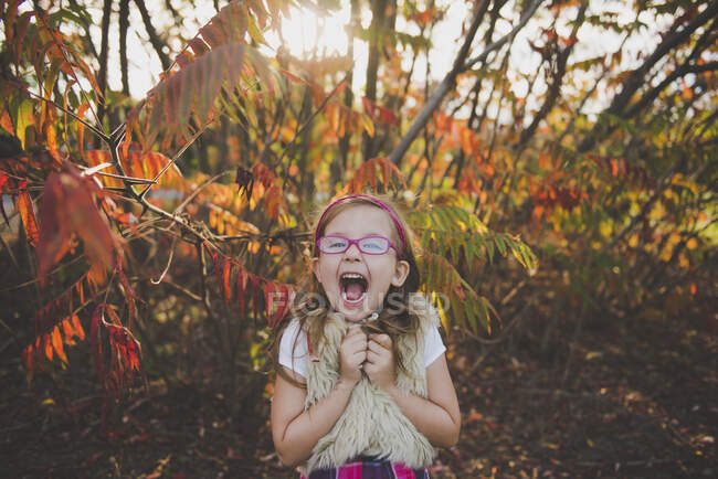 Веселая девушка с открытым ртом перед растениями осенью — стоковое фото