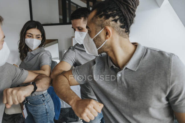 Физиотерапевты мужского и женского пола в защитных масках для лица при ударе локтем — стоковое фото