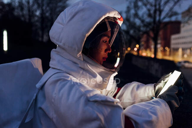 Joven astronauta usando teléfono móvil por la noche - foto de stock