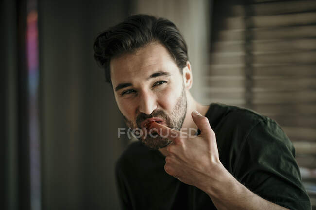 Felice uomo leccare dito mentre guardando lontano — Foto stock