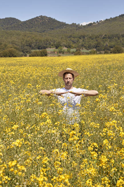 Giovane uomo che indossa cappello di paglia in piedi in campo durante la giornata di sole — Foto stock