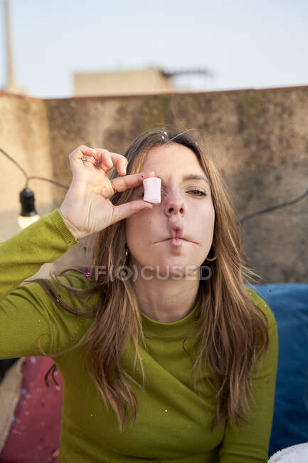 Jeune femme faisant visage tout en couvrant l'oeil avec des bonbons — Photo de stock