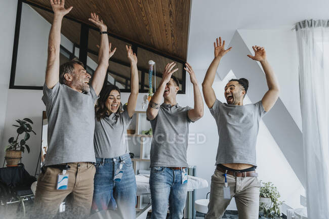 Cheerful male and female physiotherapist with arms raised having fun in practice — Fotografia de Stock