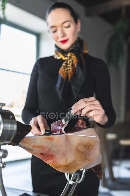 Female chef cutting ham in restaurant — Stock Photo