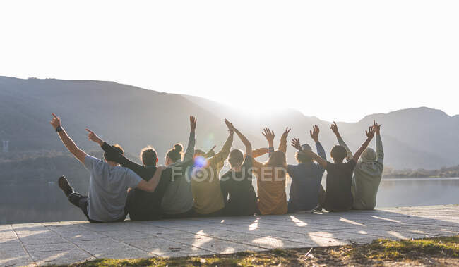 Allegro maschio e femmina amici seduti insieme sul lungomare durante la giornata di sole — Foto stock