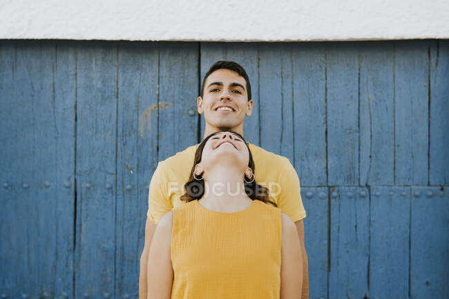 Jeune femme penchée sur un homme souriant devant un mur — Photo de stock