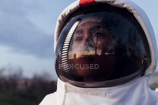 Pensiero astronauta donna guardando lontano indossando casco spaziale durante il tramonto — Foto stock