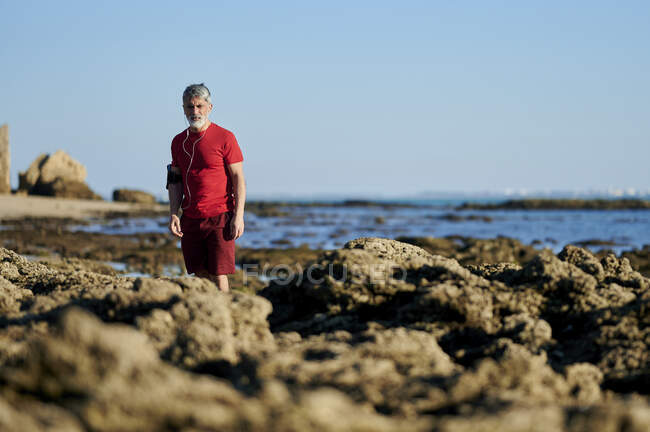 Людина стоїть на скелях на пляжі. — стокове фото