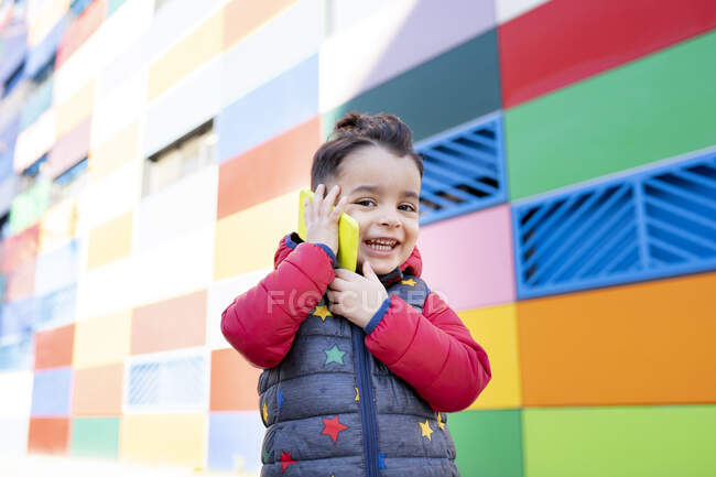 Glücklicher Junge spricht Smartphone an Wand — Stockfoto