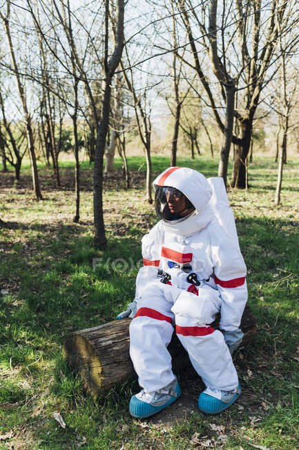 Junge Astronautin sitzt auf Holzklotz im Wald — Stockfoto