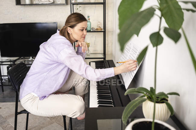 Femme moyenne adulte avec note musicale apprenant à la maison — Photo de stock