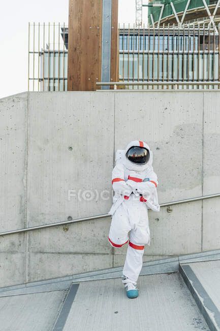 Male astronaut standing with arms crossed leaning on wall - foto de stock