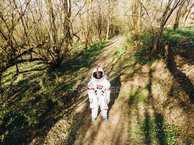 Самка астронавт у скафандрі стоїть на лісовій стежці — стокове фото