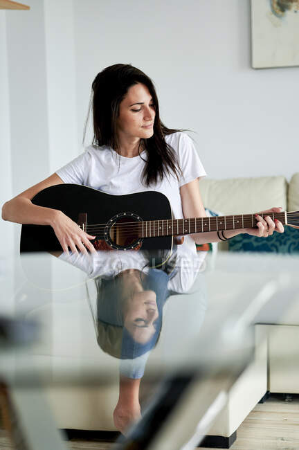 Mitte erwachsene Frau spielt zu Hause Gitarre — Stockfoto