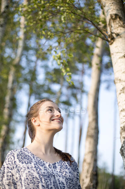 Jeune femme souriante profitant de la nature dans une forêt — Photo de stock