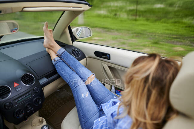 Mulher adulta média com pernas cruzadas no tornozelo relaxante no carro — Fotografia de Stock