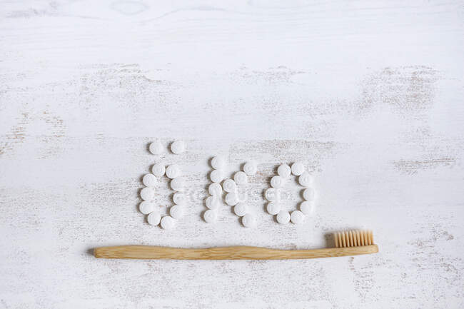 Зубная щетка из бамбука с таблеткой зубной пасты на текстурированном фоне — стоковое фото