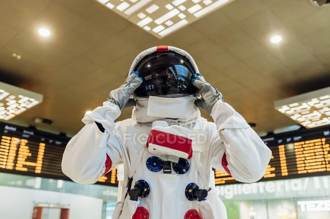 Male astronaut wearing space helmet while standing at arrival departure board — Stock Photo