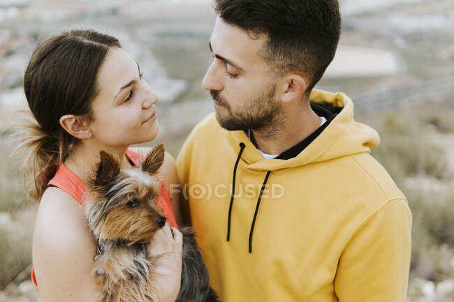 Junger Mann sieht Frau mit Hund in der Hand an — Stockfoto
