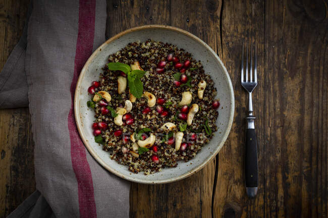 Bowl of vegan quinoa salad with cashews, pomegranate seeds and mint — Stock Photo