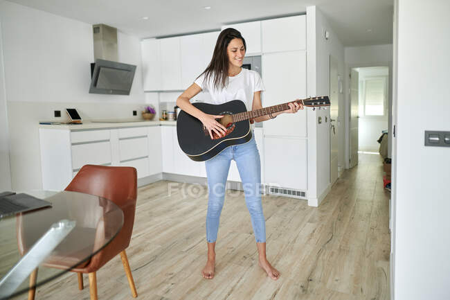 Smiling woman playing guitar at home — Stock Photo