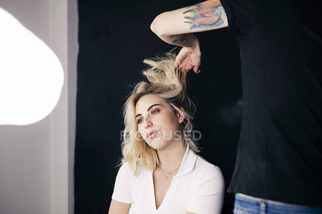 Cabeleireiro feminino styling cabelo de modelo em estúdio — Fotografia de Stock