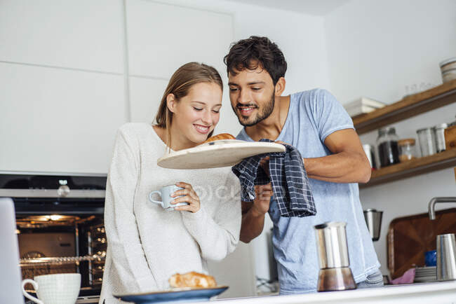 Mann zeigt Freundin in Küche zu Hause frisch gebackenes Croissant — Stockfoto