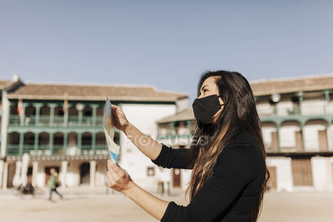 Turista con máscara protectora comprobar mapa - foto de stock
