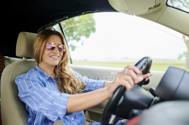 Mujer adulta sonriendo mientras conduce el coche - foto de stock