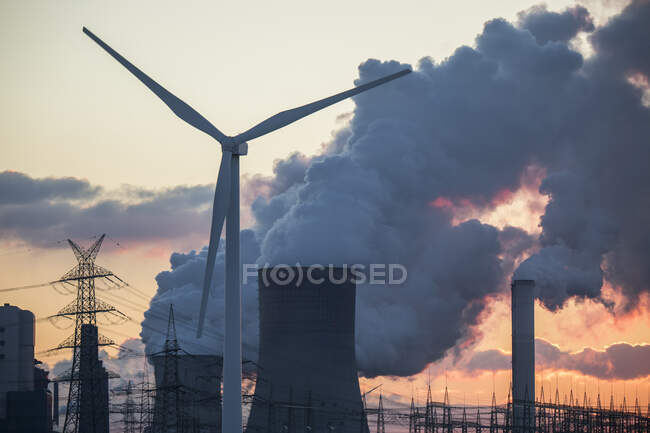 Германия, Северный Рейн Вестфалия, Нидерэраузем, ветряные турбины и электростанция с лигнитом на закате — стоковое фото