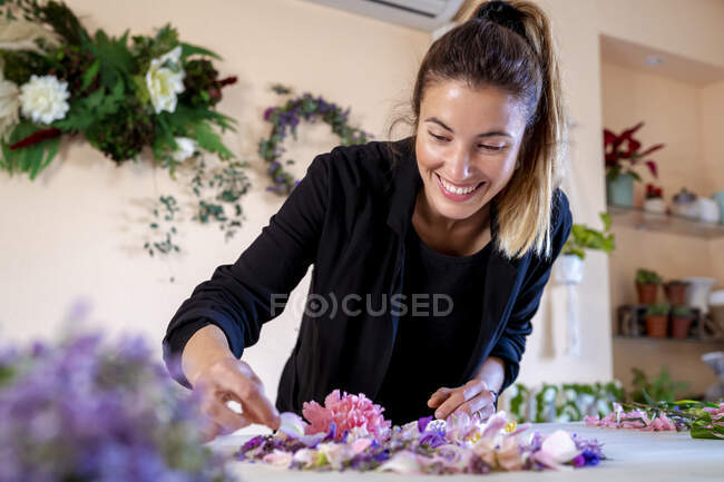 Happy female florist making flower decoration at workshop — Stock Photo