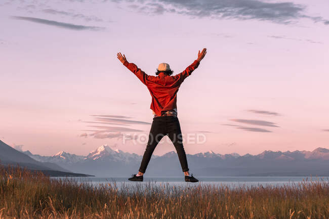 Нова Зеландія, Кентербері, вид молодого чоловіка, що стрибнув над озером Пукакі на заході сонця. — стокове фото