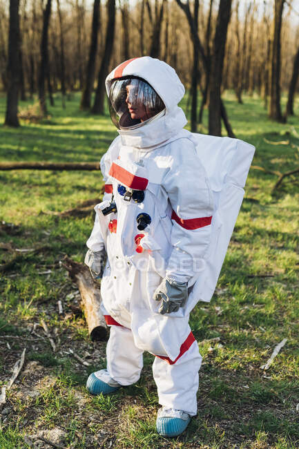 Exploradora mulher vestindo terno espacial e capacete em pé na floresta — Fotografia de Stock