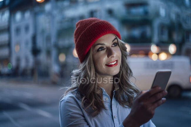 Empresária segurando telefone celular enquanto olha para longe — Fotografia de Stock