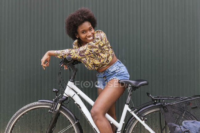 Hermosa mujer apoyada en bicicleta por la pared - foto de stock