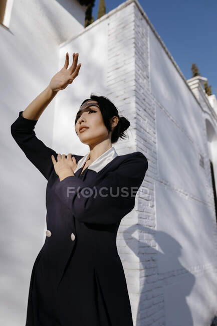 Young woman shielding eyes while standing in front of white building during sunny day — Stock Photo
