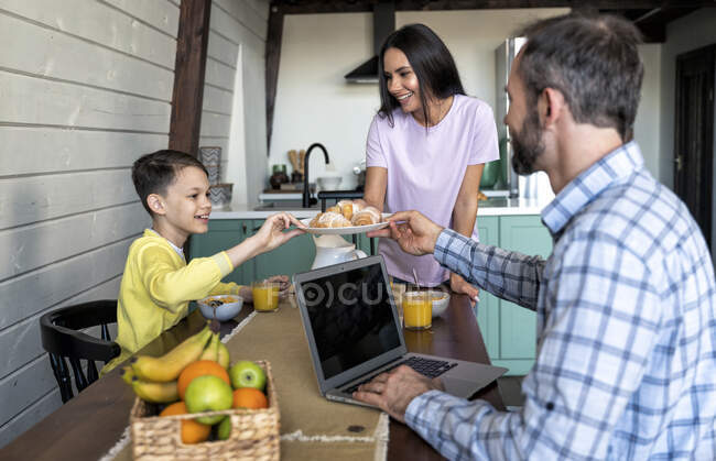 Mère servant des croissants à la famille sur la table à manger à la maison — Photo de stock