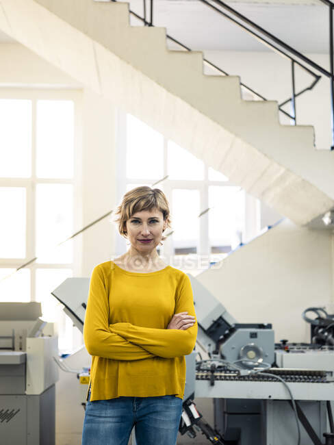 Confident female owner standing with arms crossed in printing workshop — Stock Photo