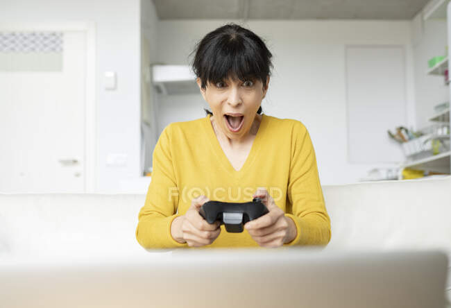 Mulher surpresa jogando videogame em casa — Fotografia de Stock